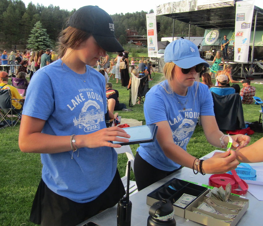 Sarah Jermano, left, and Kat Ashby, who work at the Evergreen Lake House, sell drink tickets at the concert.